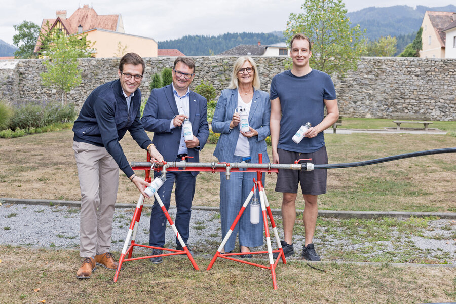 Vier Personen mit Wasserflaschen vor einer Testapparatur mit Wasserhähnen in Kärnten