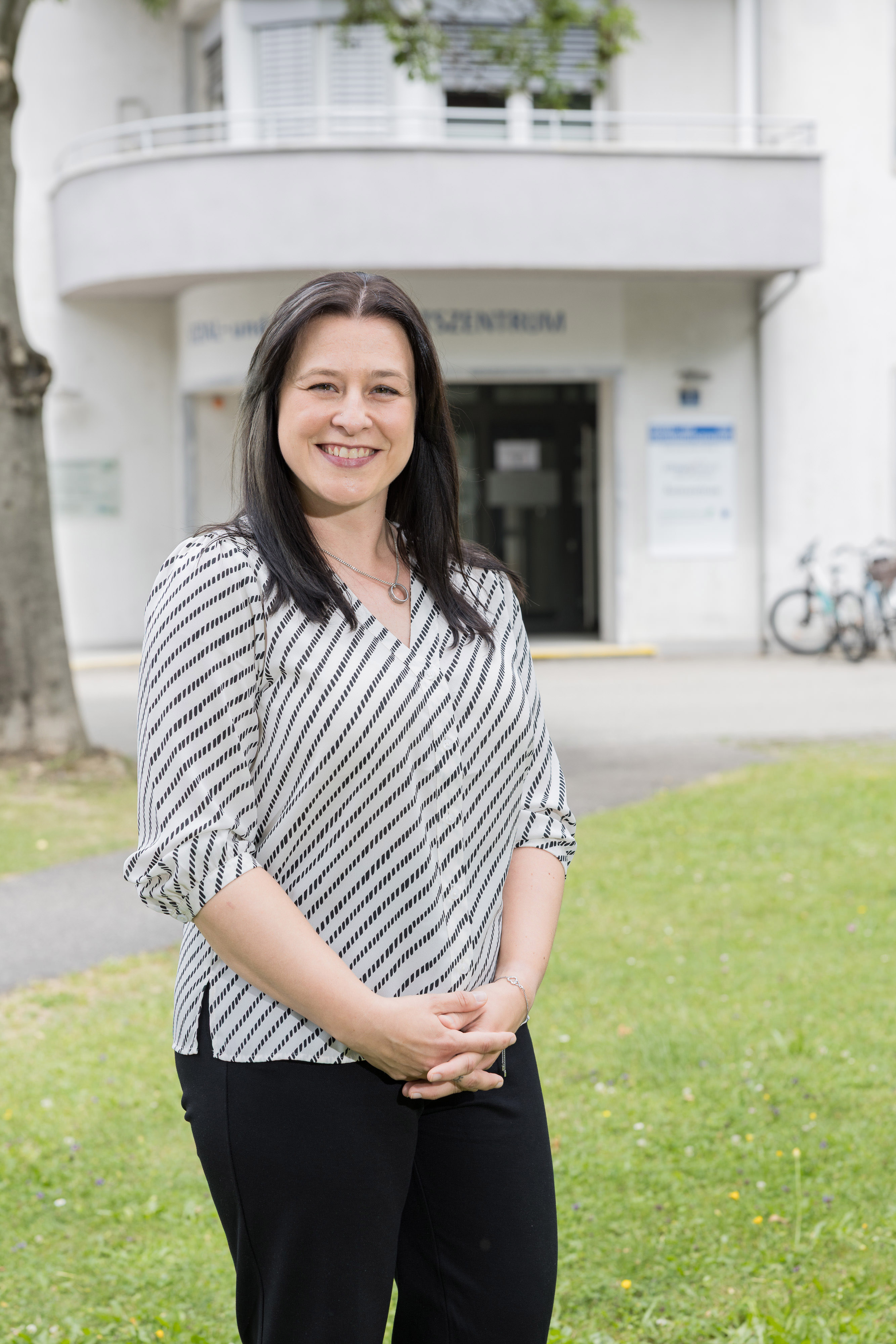 Frau Dr. Erika Müller, Ärztin, lächelt vor dem Gesundheitszentrum in Wien.